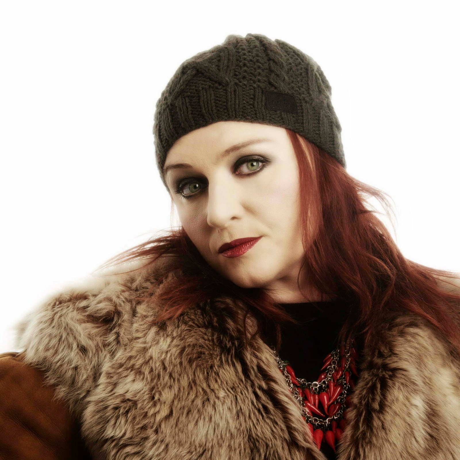 Headshot of Katherine Ellis against a white background. She is wearing a knittted hat and a fur coat.