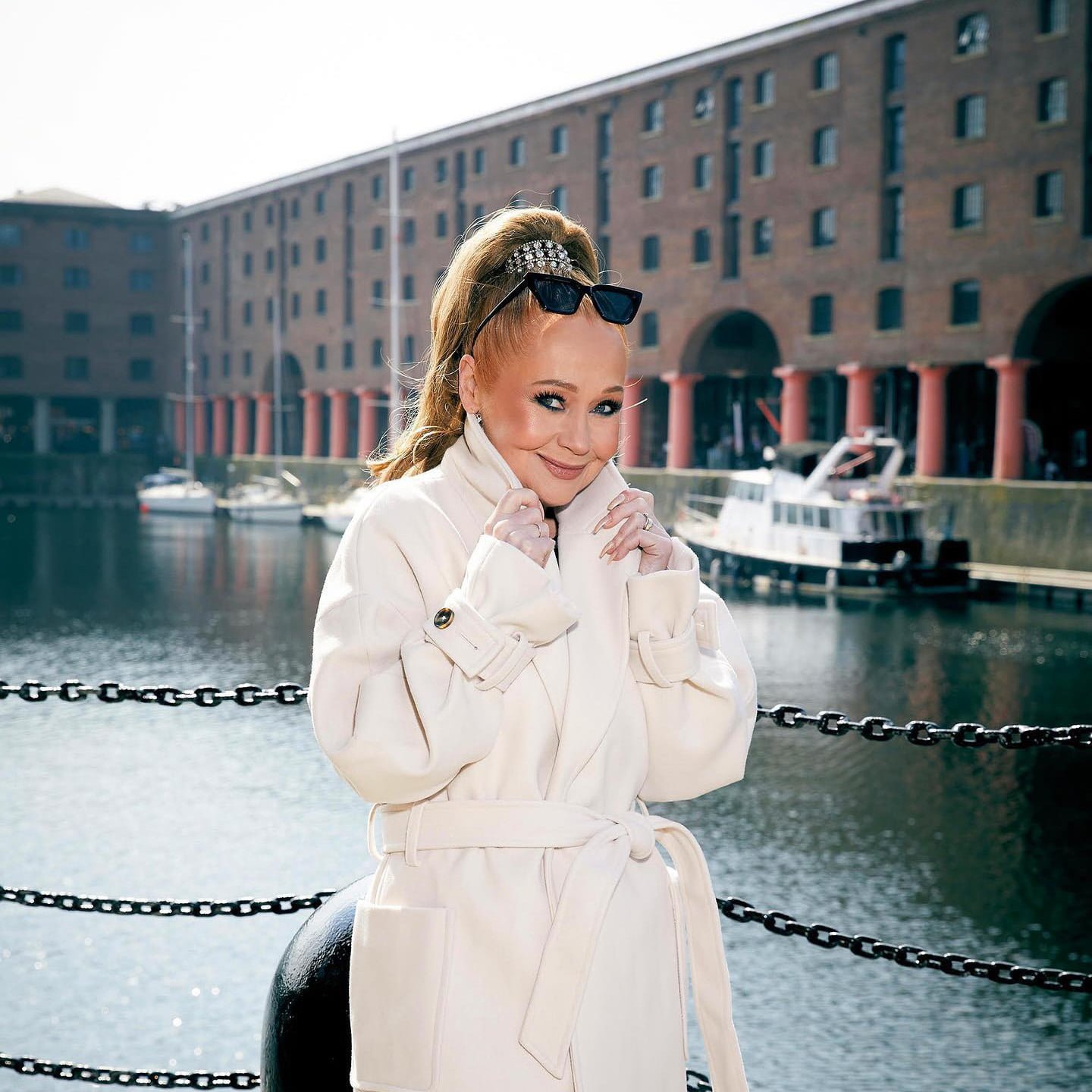 Sonia wearing a light-coloured coat at The Royal Albert Docks.