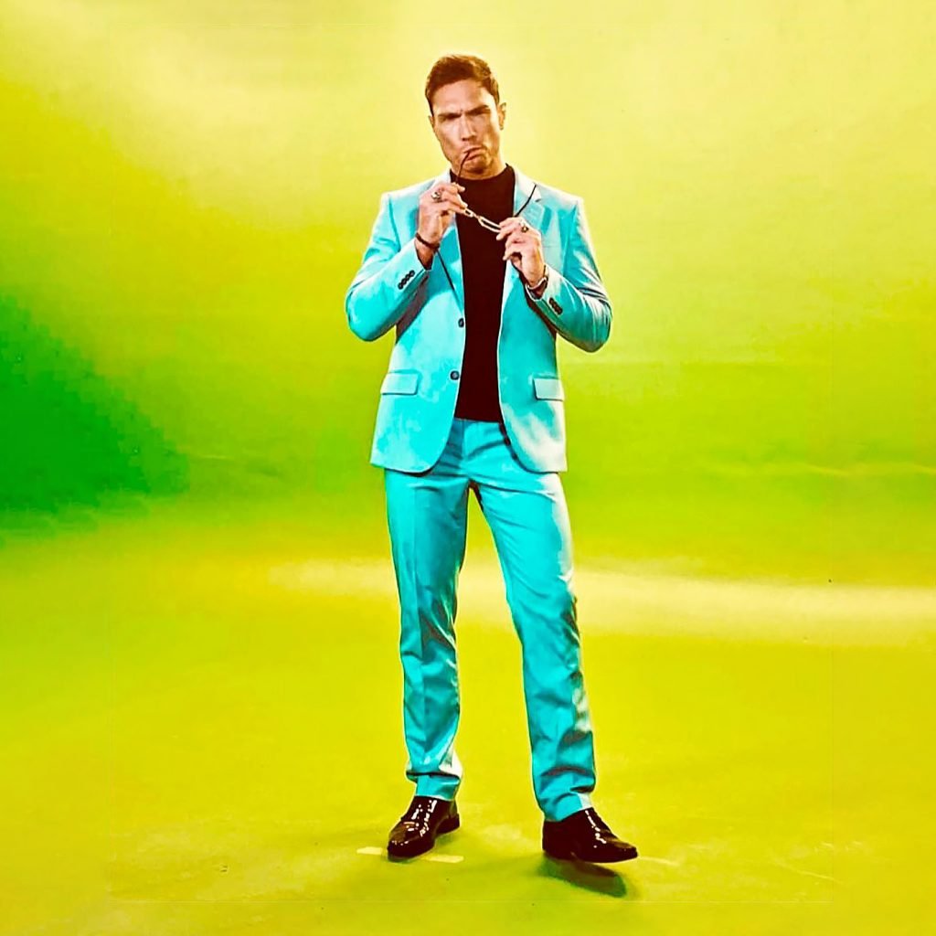 Nikk Mager posing against a green backdrop.